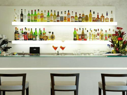 un bar con tre sedie e bottiglie di alcolici di Mercure Hotel Rimini Artis a Rimini