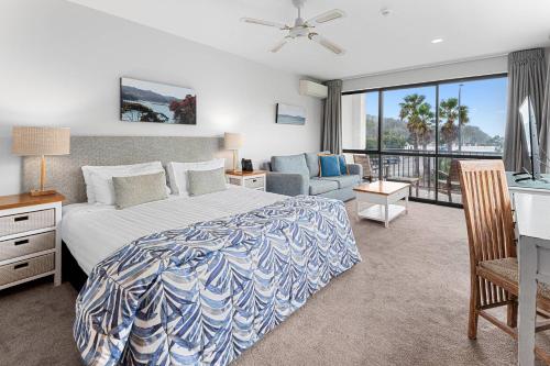 a bedroom with a bed and a couch and a window at Quality Hotel Oceans Tutukaka in Tutukaka