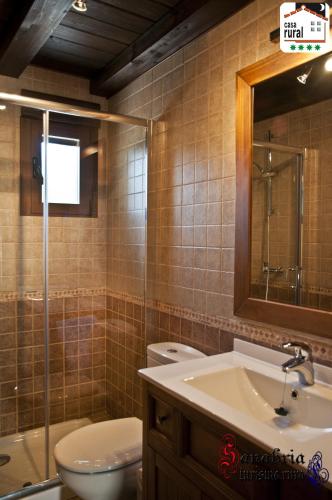 a bathroom with a toilet and a sink and a mirror at Casa Rural "La Noria" in El Puente
