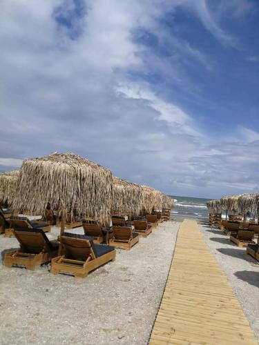a row of chairs and straw umbrellas on a beach at Building Stefan Resort 2 Mamaia Nord - Studio 804 in Năvodari
