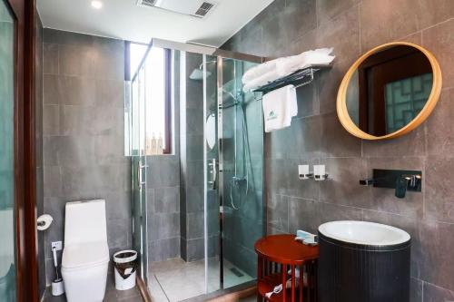 a bathroom with a shower and a toilet and a mirror at Book and Bed-ChongMing in Shanghai