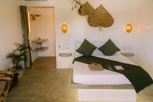 a bedroom with a bed with green pillows at SAMPA El Nido in El Nido