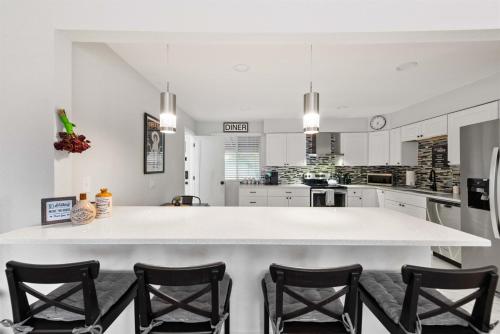a large kitchen with a large white island with chairs at Modern 4BR Retreat Private Yard - 10 Min to DEN in Arvada
