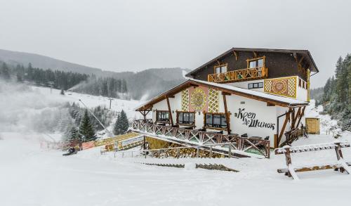 a building in the snow in front of a mountain at Chalet CrepDeChine Hotel in Bukovel