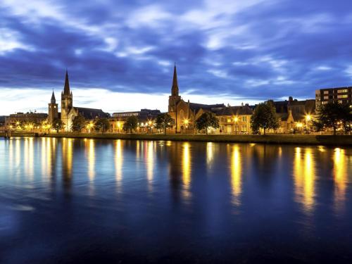 a city lit up at night with a body of water at Mercure Inverness Hotel in Inverness