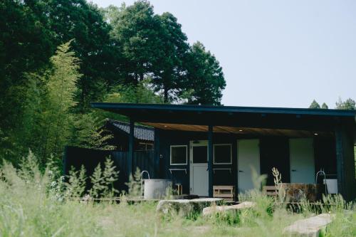 a black building with a porch and trees at Takigahara Craft & Stay in Komatsu
