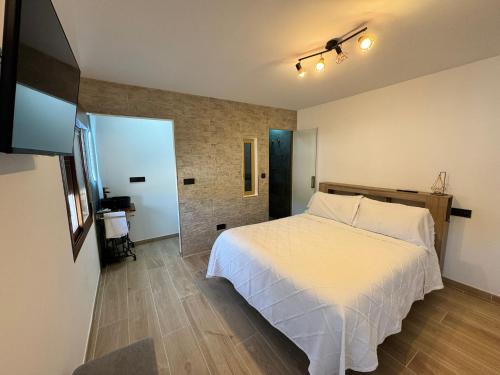 a bedroom with a white bed and a brick wall at Verde in Alcalá del Júcar