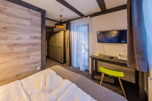 a bedroom with a bed and a desk with a television at Chalet CrepDeChine Hotel in Bukovel