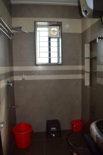 a bathroom with two red stools and a window at Everfreshhighviewcottage in Ooty