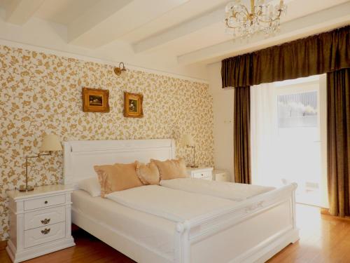 a white bed in a bedroom with floral wallpaper at Allegro Hotel in Ljubljana
