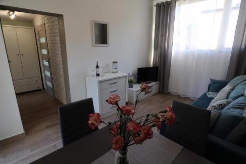 a living room with a couch and a table with flowers at Paradiso Park in Pobierowo