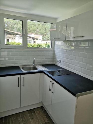 a kitchen with white cabinets and a sink and a window at Paradiso Park in Pobierowo