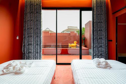 two beds in a room with a large window at Afro Pool Villa Bangsean 01 in Ban Puk (2)