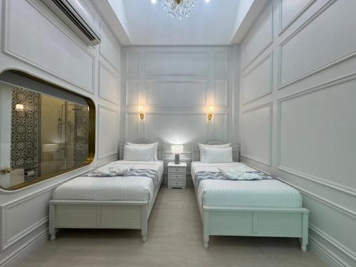 two beds in a room with white walls at Best House Luang Prabang in Luang Prabang