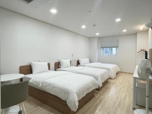three beds in a room with white walls at Bonghwang Inn BonghwangMansion2 in Gyeongju