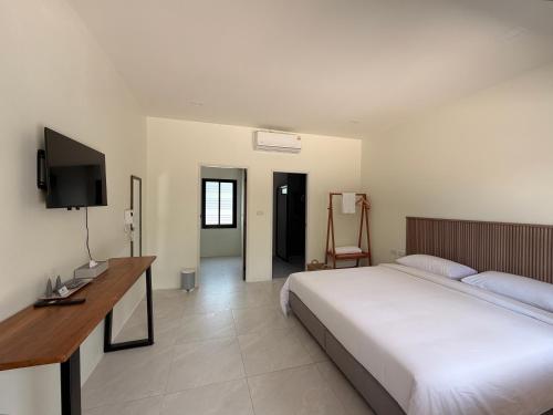 a bedroom with a bed and a desk and a television at Wanwichai Room in Ban Lam Ru (1)