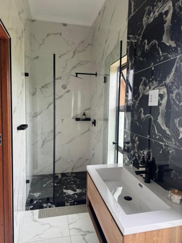 a bathroom with a shower and a white sink at Eye with a view in Eikenhof