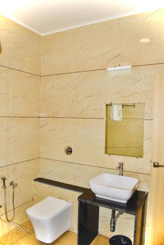 a bathroom with a white sink and a toilet at Hotel Samrat International in Mount Ābu