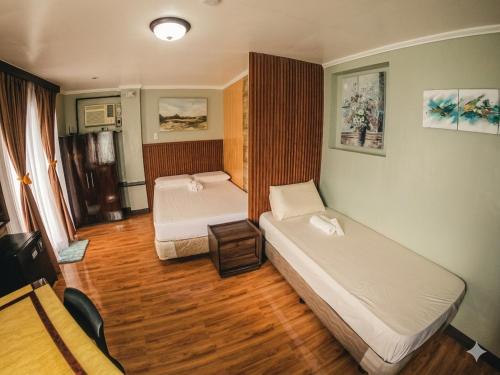 a room with two beds in a room with wooden floors at Marjhun's Apartelle in Jagna