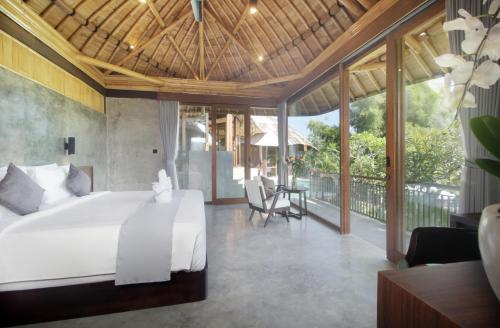 a bedroom with a white bed and a balcony at Babakan Hill Villas in Jasri