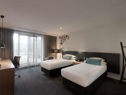 ein Hotelzimmer mit zwei Betten und einem Schreibtisch in der Unterkunft The Como Melbourne in Melbourne
