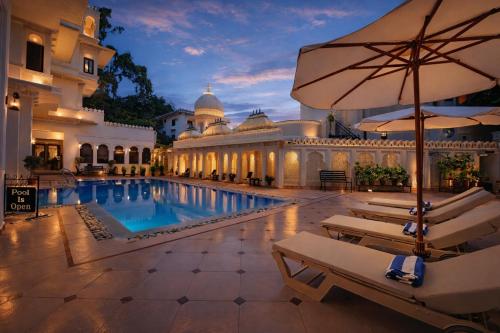 a hotel pool with chairs and an umbrella at Swaroop Vilas - Lake Facing Boutique Hotel in Udaipur