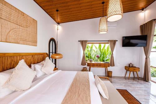 a bedroom with a white bed and a television at Sake Bali Suites in Tegalalang
