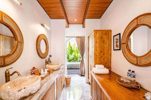 a bathroom with two sinks and two mirrors at Sake Bali Suites in Tegalalang