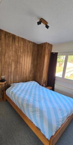 a bedroom with a bed with a wooden wall at Charmant petit appartement in Ovronnaz