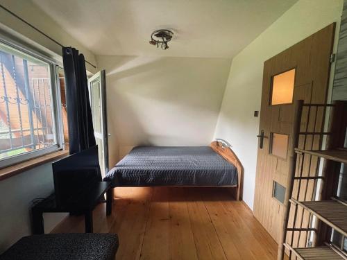 a small room with a bed and a window at Domek nad Wiarem in Huwniki