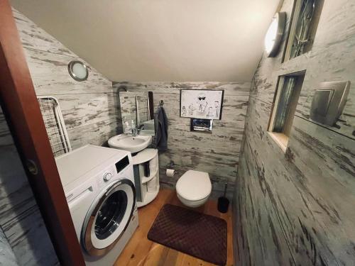 a bathroom with a washing machine and a sink at Domek nad Wiarem in Huwniki