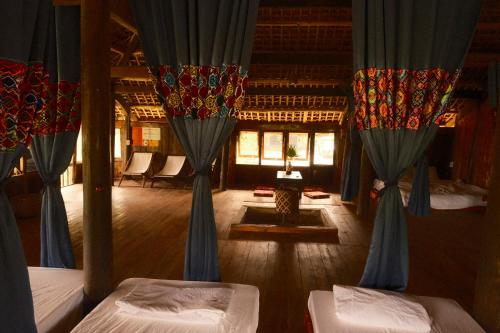 two beds in a room with blue curtains at La Beauté Nghia Do in Nghĩa Ðô