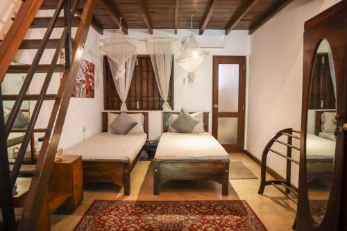 a living room with two beds and a staircase at Colonial Residence Kandy Boutique Bungalow in Kandy