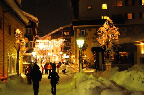 people walking down a snowy street at night with christmas lights at Sporthotel St. Anton in Sankt Anton am Arlberg