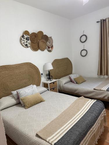a bedroom with two beds and a table with a lamp at Cortijo Loma del Estanque in Monachil