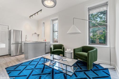 a living room with two green chairs and a glass table at The Neighborhood Hotel - Lincoln Park 501 - Three Bedroom Penthouse in Chicago