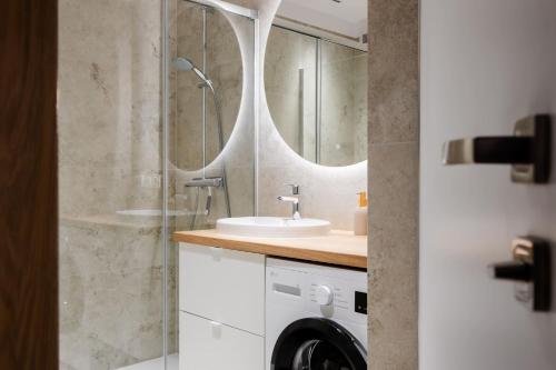 a bathroom with a shower and a sink and a washing machine at Apartament Harmonia Baltic in Sarbinowo