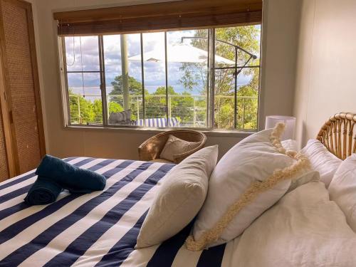 a bedroom with a bed with pillows and a window at Sanctuary Spaces - Wategoes Beach Shack in Byron Bay