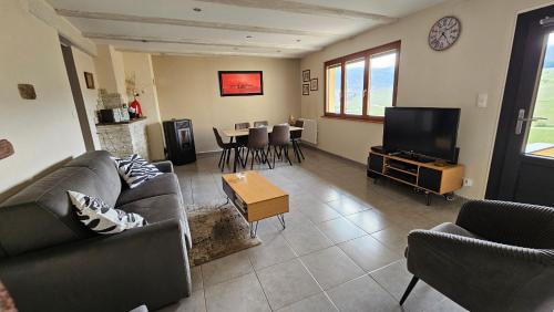 a living room with a couch and a tv at Le Zell in Zellenberg