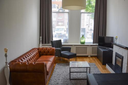 a living room with a leather couch and two chairs at Stadshotel centrum Deventer, 2 appartementen in Deventer