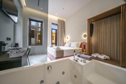 a bathroom with a tub and a bed in a room at Omma Suites in Rethymno