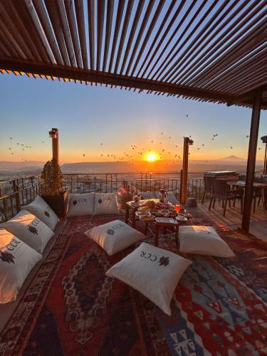 a living room with a couch and a sunset at CCR Cappadocia Cave Resort &Spa in Eskiömerler
