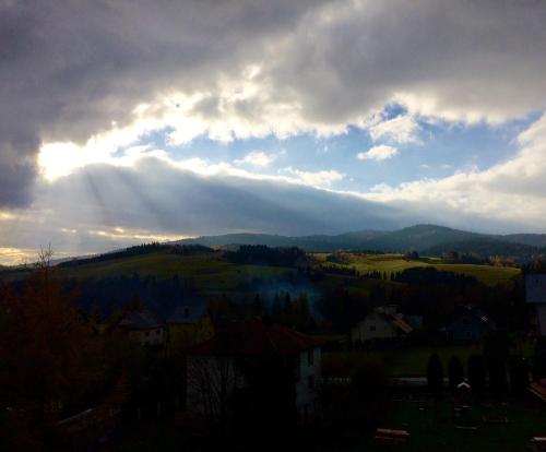 a cloudy sky with the sun shining on a mountain at Willa Hamernik AGROTURYSTYKA in Tylicz