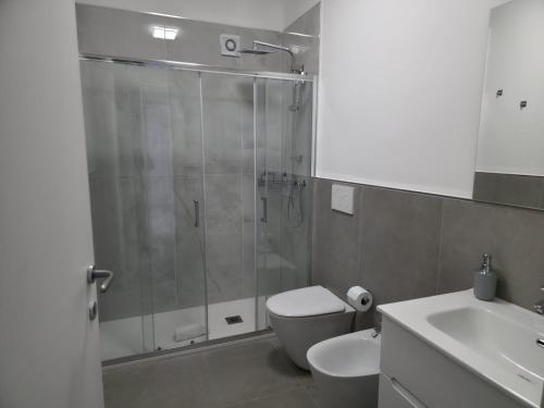 a bathroom with a shower and a toilet and a sink at Moonlight Apartment in Schisò