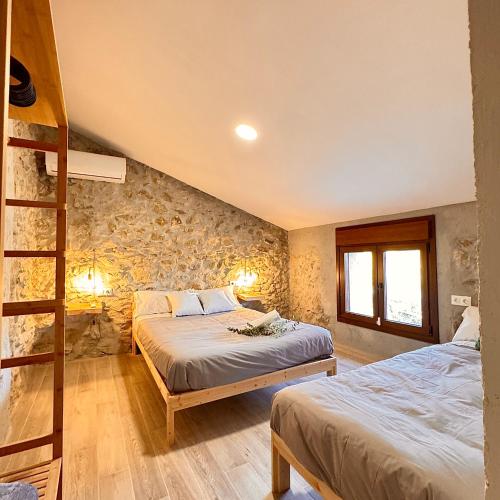 a bedroom with two beds and a stone wall at Villa Jimena in Periana