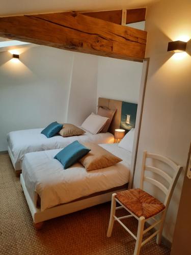 a bedroom with two beds and a chair at Gîte du Petit Moulin in Réaumur