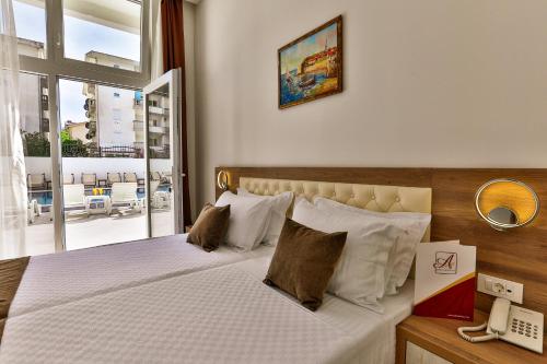 a bedroom with a bed with white sheets and a phone at Sutomore Akapulco Hotel in Sutomore