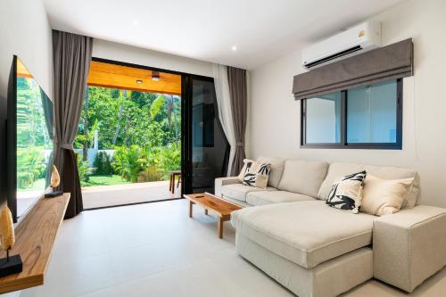 a living room with a couch and a table at Siva Pool Villa in Chaloklum
