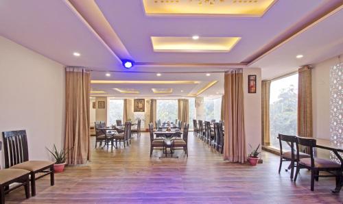 a dining room with tables and chairs and windows at Hotel Rama Hindustani in Jaipur