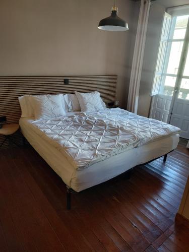 a bed with white sheets and pillows in a bedroom at Pension Casa Simon in Treacastela